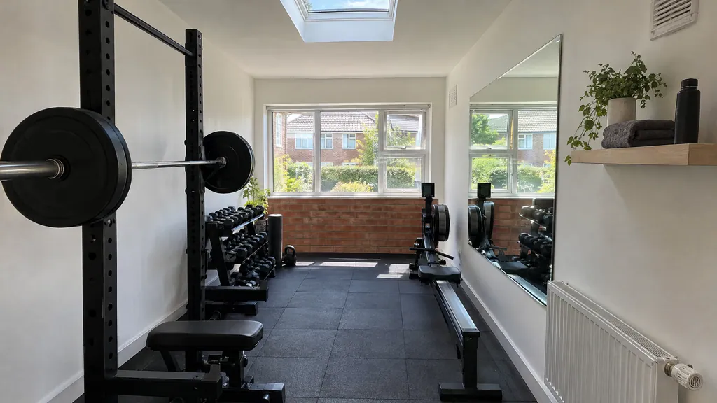 Garage conversion idea in a Castleknock semi: a bright home gym with rubber flooring, a rack and a wall mirror.