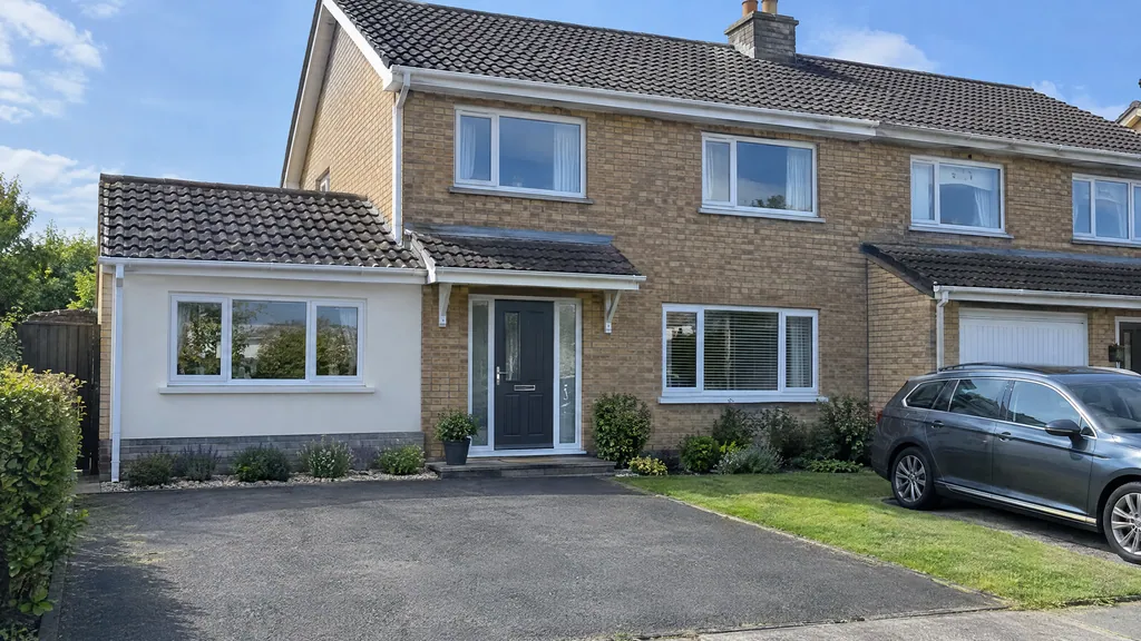 Garage conversion vs extension: a converted single garage with a new window and rendered infill on a 1990s buff-brick semi in Lucan.